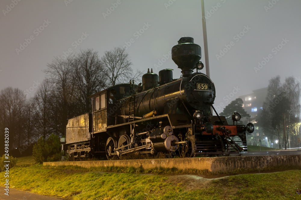 Obraz premium KOUVOLA, FINLAND - NOVEMBER 7, 2018: Old steam locomotive as an exhibit at the Kouvola railway station in Finland at night.