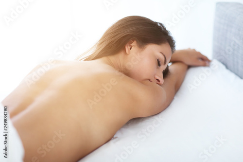 Adult naked woman lying in bed in the morning