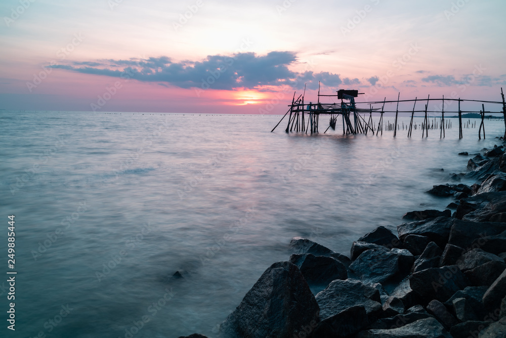 Wooden Jetty with the rocky seaside during sunset. Long exposure.
