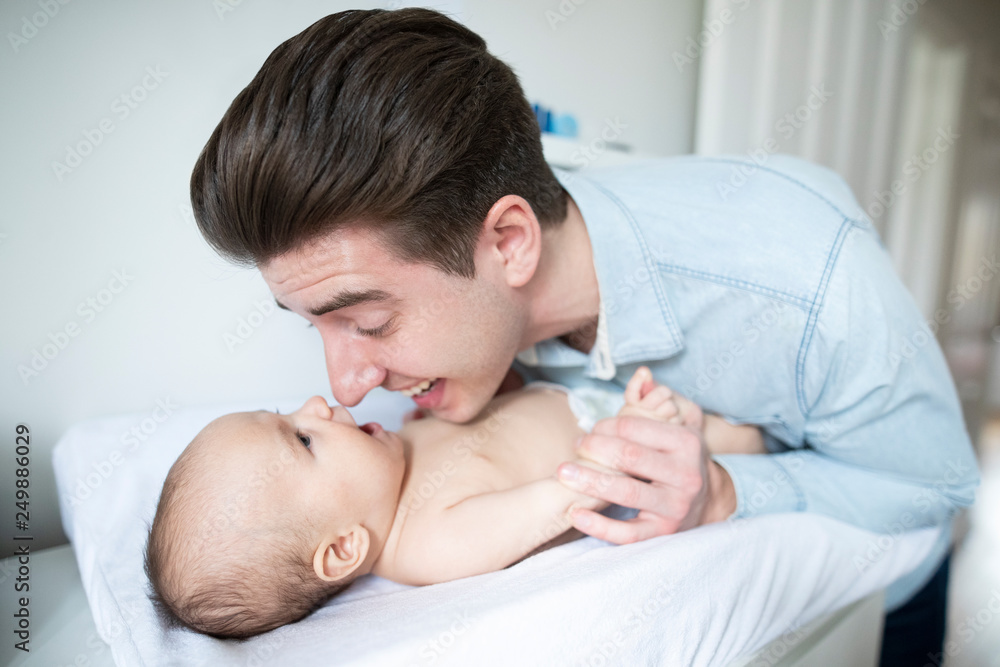 Father In Nursery At Home Changing Baby Sons Daiper Father In Nursery At Home Changing Baby Sons Daiper