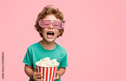 Screaming boy in glasses holding popcorn