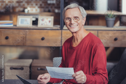 Positive pensioner feeling satisfied with his bills and smiling