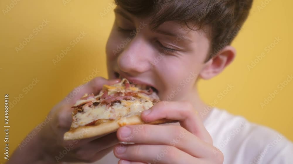 Pizza. happy teen boy eating a slice of pizza concept. teenage boy hungry eats a slice of pizza. slow motion video. lifestyle pizza fast food concept Pizza. happy teen boy eating a slice of pizza concept. teenage boy hungry eats a slice of pizza. slow motion video. lifestyle pizza fast food concept