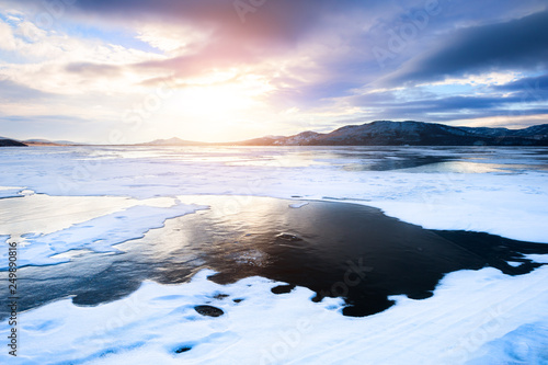 Snow and ice on the frozen lake at sunset. photo