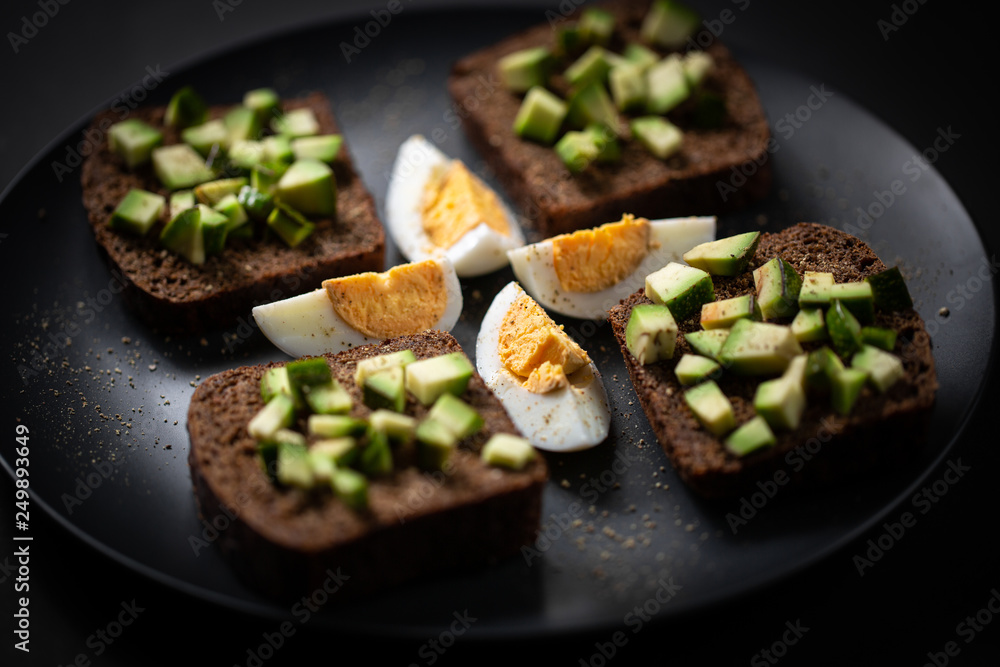 toast with avocado and egg on a black plate toast with avocado and egg on a black plate