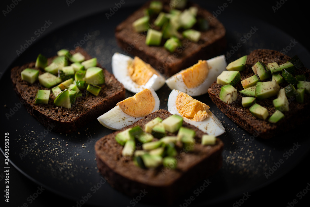 toast with avocado and egg on a black plate toast with avocado and egg on a black plate