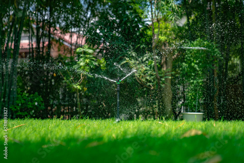 fresh water splash from the sprinkle pole settle in the grass feild in the outdoor garden.