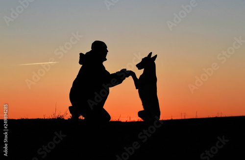 A man and a dog against the backdrop of an incredible sunset