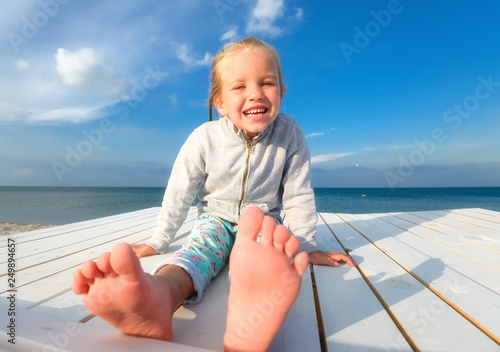 Little pretty girl on summer beach. Cheerful little girl laughs on the background of blue sky and summer sea. photo