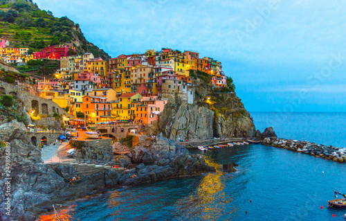 Fototapeta Naklejka Na Ścianę i Meble -  Manarola traditional typical Italian village in National park Cinque Terre with colorful multicolored buildings houses on rock cliff and marine harbor, night evening view, La Spezia, Liguria, Italy