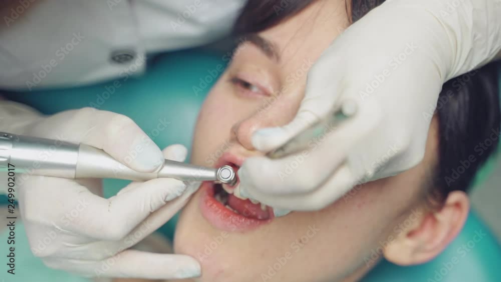 Professional dentist working with patient at dental office. Air flow method of cleaning teeth with sandblasting machine. Close-up Professional dentist working with patient at dental office. Air flow method of cleaning teeth with sandblasting machine. Close-up