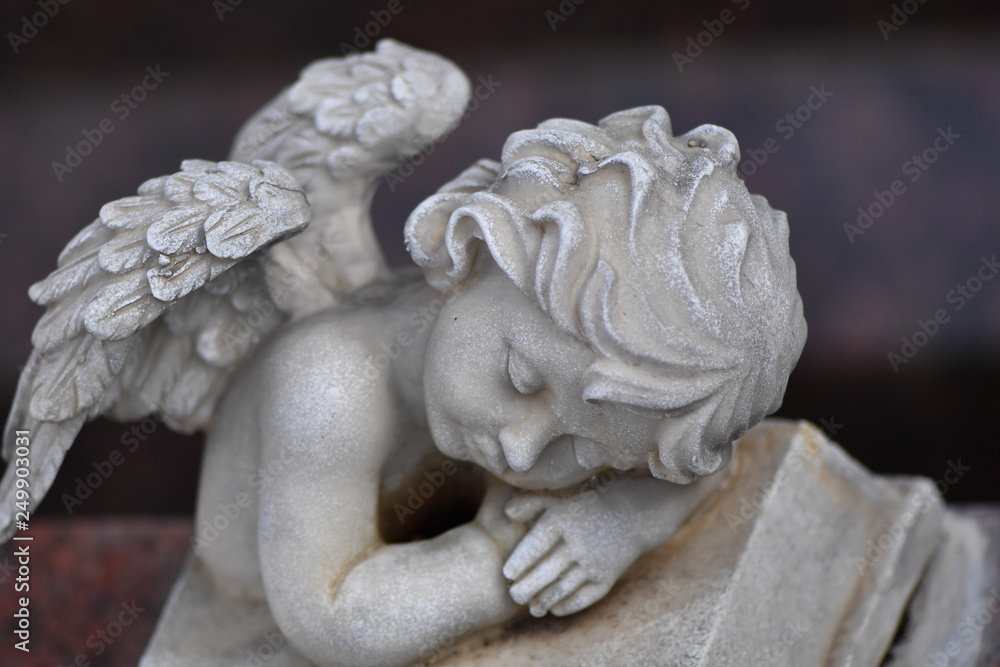 A sandstone sculpture of a small sleeping angel.