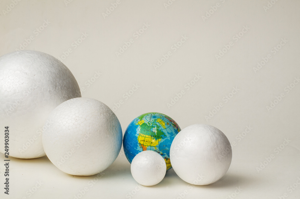 Four white balls of plastic, different sizes and globe lie in the plane of the blue background, in a dense composition, copy space. Four white balls of plastic, different sizes and globe lie in the plane of the blue background, in a dense composition, copy space.