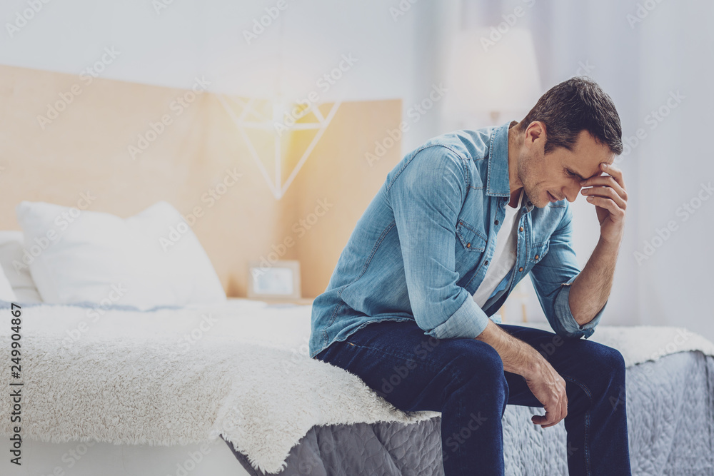 Tired man touching elbow while thinking Tired man touching elbow while thinking