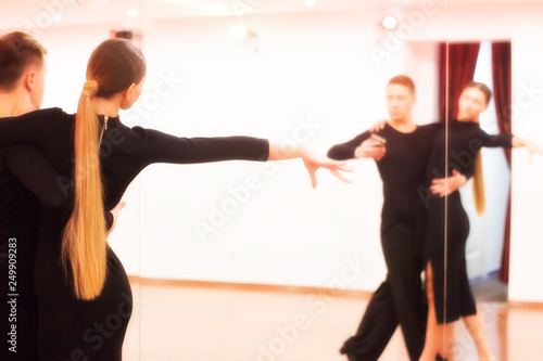 The teacher teaches to dance a young woman in front of a mirror