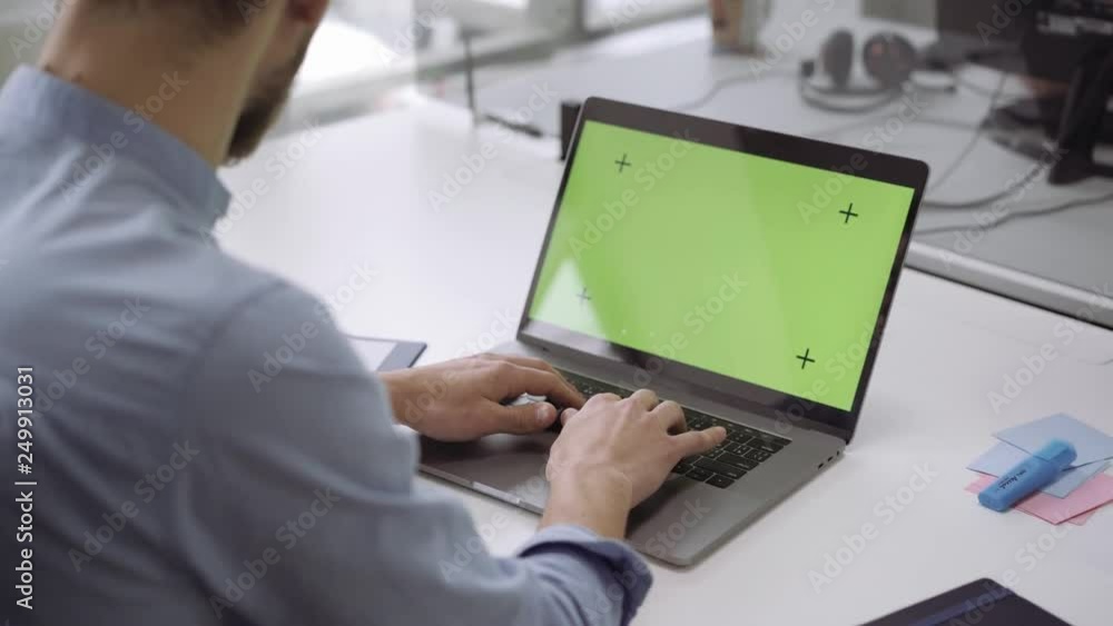 Close up hands on laptop with green screen on white table Close up hands on laptop with green screen on white table