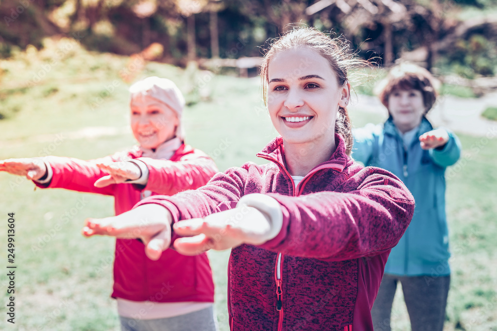 Fototapeta premium Young dark-eyed fitness trainer training retired women