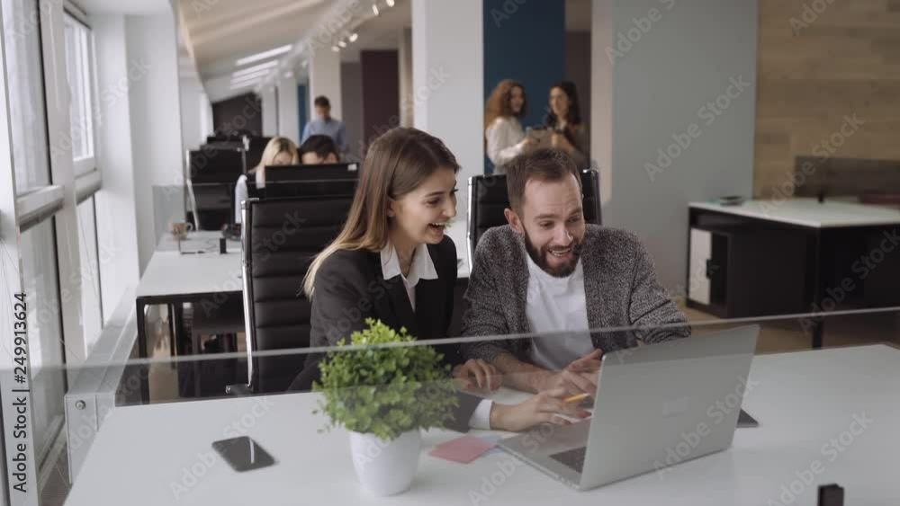 Candid creative busines man and woman discuss project in office and look at something fun. Happy moments. Medium shot Candid creative busines man and woman discuss project in office and look at something fun. Happy moments. Medium shot