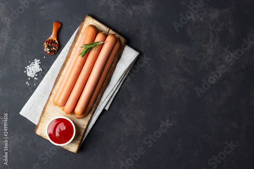 Принти на полотні Raw frankfurter sausages with ketchup on cutting board