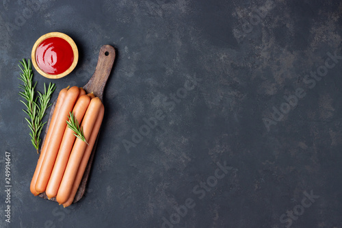 Принти на полотні Raw frankfurter sausages with ketchup on cutting board