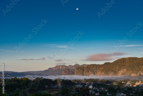 fog in the valley of Vinales with full moon palm trees and mountains
