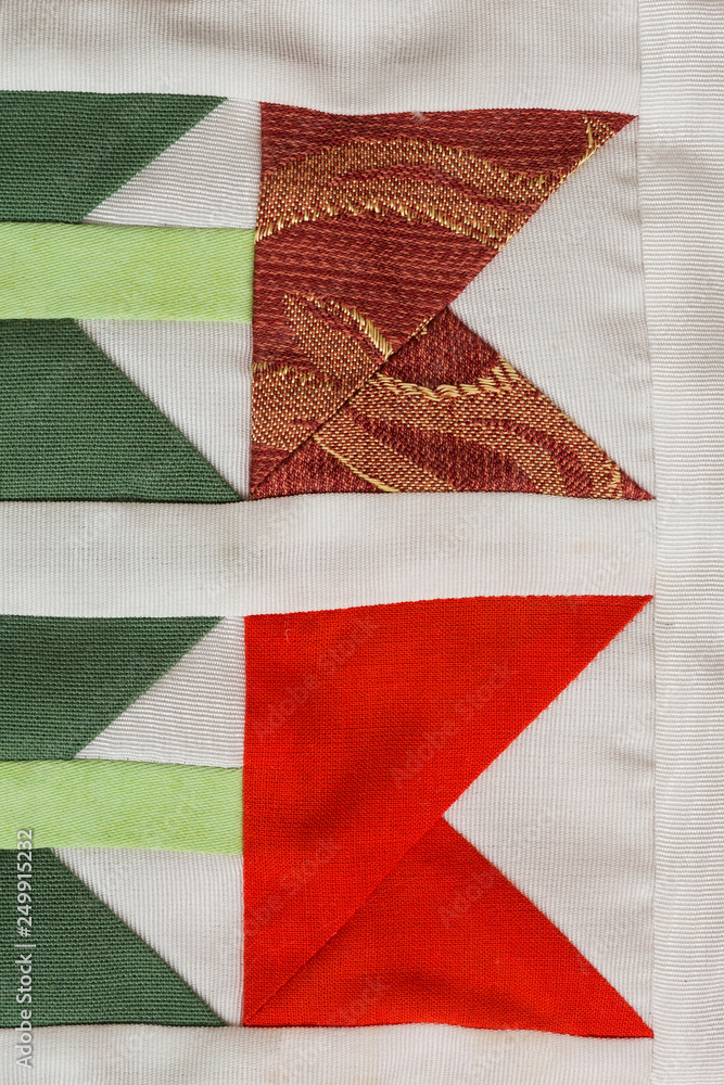 Fototapeta premium patchwork, sewing, fashion concept - macro on beautiful quilt sewn from scraps of colored cloths in feed of certain geometric shapes, close-up on different flaps of stitched material, flat lay.