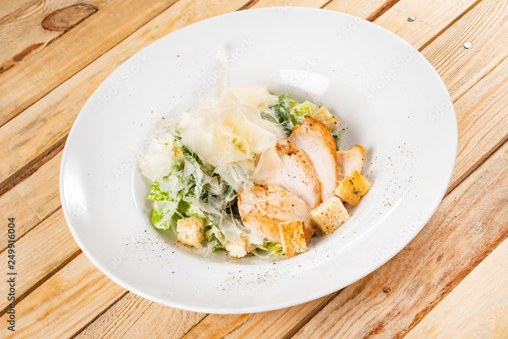 Fresh caesar salad in white plate, wooden background Fresh caesar salad in white plate, wooden background