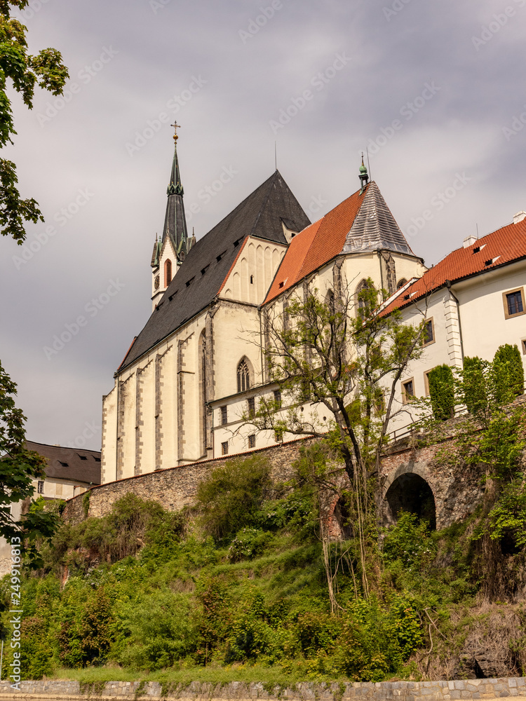 Obraz premium Widok miasta Český Krumlov, wpisanego na Listę Światowego Dziedzictwa UNESCO, w Czechach z zabytkowymi budynkami, kościołami i wąskimi uliczkami na tle błękitnego nieba