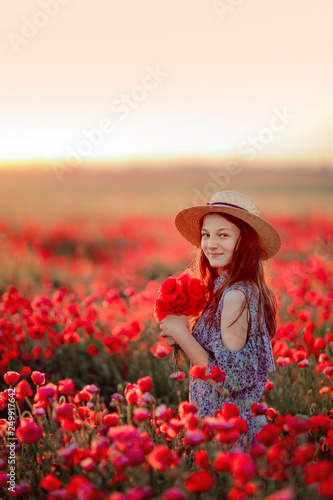 young girl in field of poppies in the bright hat