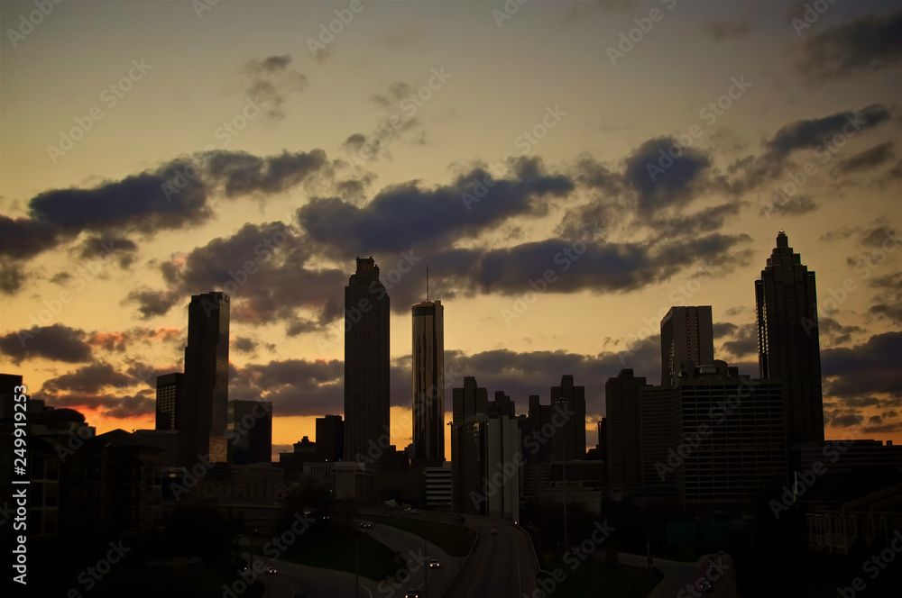 A dramatic silhouette of a cluster of buildings set against a golden sunset.
