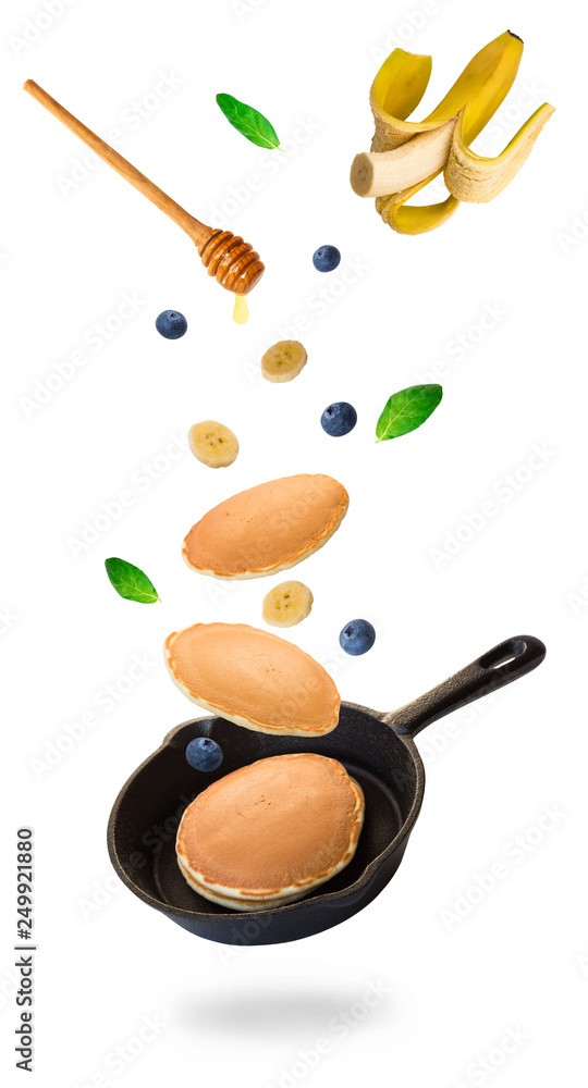 Pancakes, blueberries and banana flying into iron skillet Pancakes, blueberries and banana flying into iron skillet
