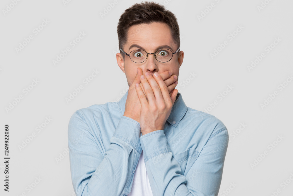 Shocked scared man with surprised face covering mouth with hands Shocked scared man with surprised face covering mouth with hands