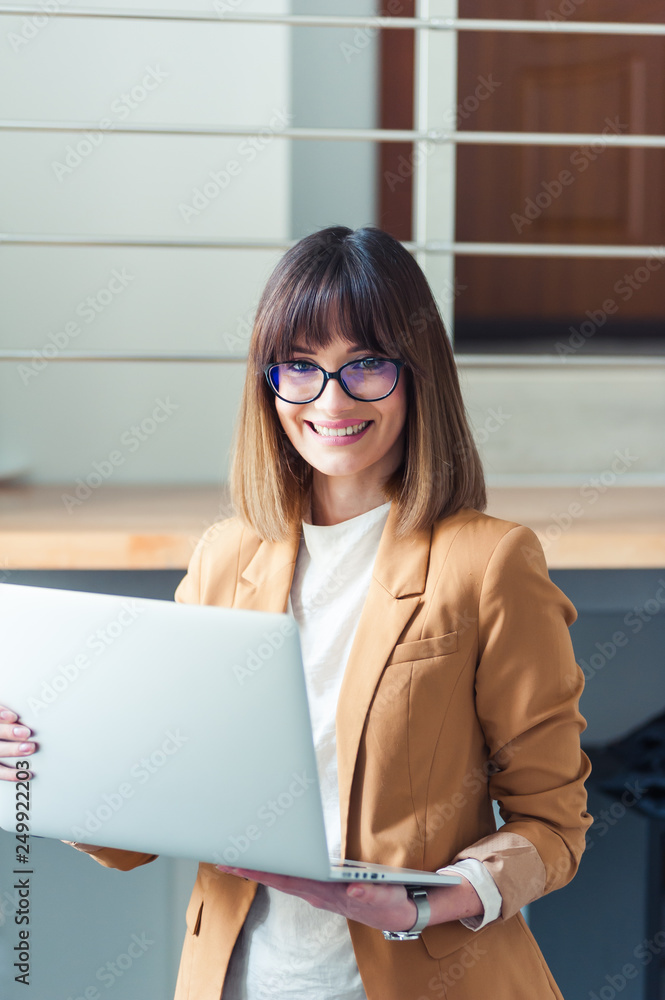 Beautiful woman designer freelancer in eyeglasses wearing casual using laptop in white office Beautiful woman designer freelancer in eyeglasses wearing casual using laptop in white office