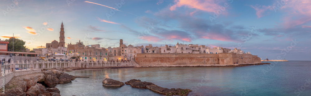 Fototapeta premium Sunset panorama of Monopoli harbor in the Metropolitan City of Bari and region of Apulia ( Puglia ) , Italy and beautiful illuminated cathedral Basilica Concattedrale Maria Santissima della Madia