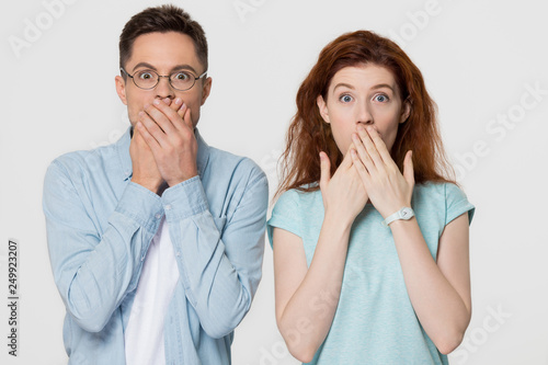 Shocked scared couple covering mouth with hands looking at camera