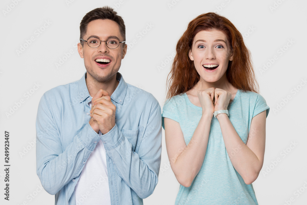 Excited couple looking at camera with delight isolated on background