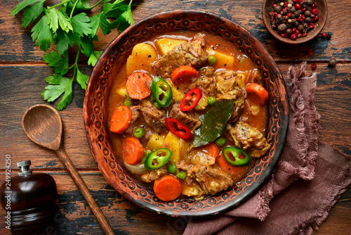 Fototapeta Naklejka Na Ścianę i Meble -  Meat stew with potato, carrot and green pea in a tomato sauce.Top view with copy space.