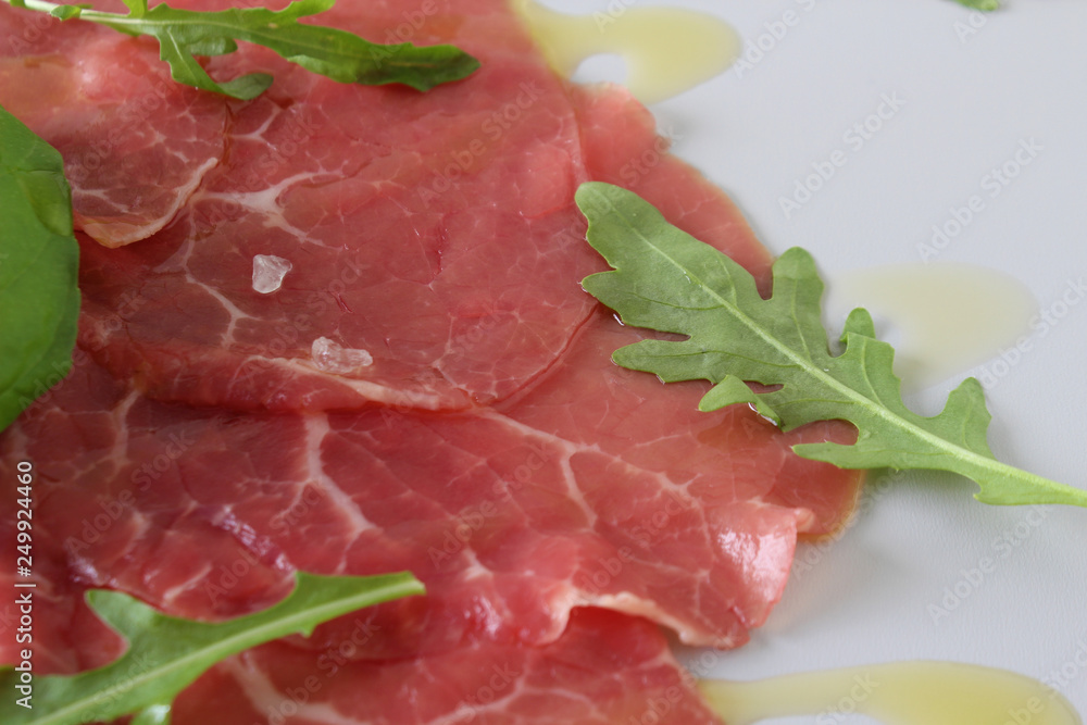 beef carpaccio on a light gray basil background beef carpaccio on a light gray basil background