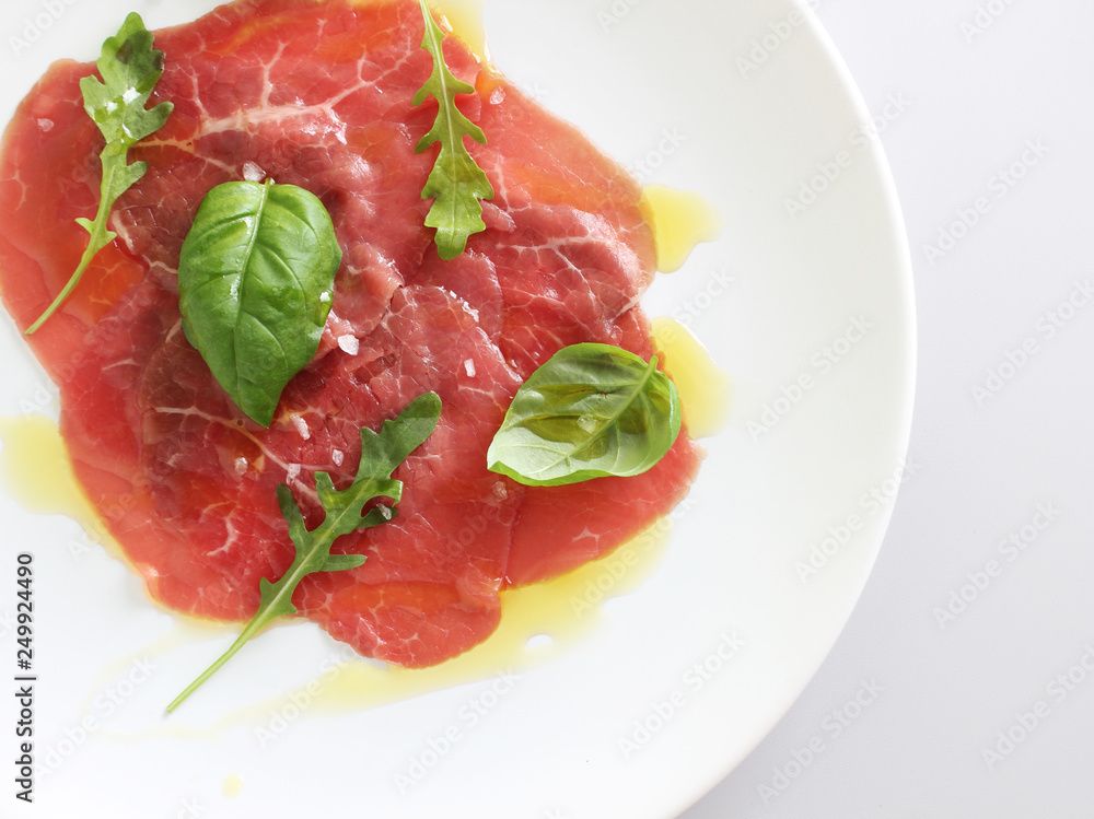 beef carpaccio on a light gray basil background