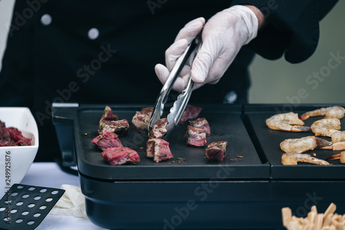 Cook prepares shrimp and grilled meat