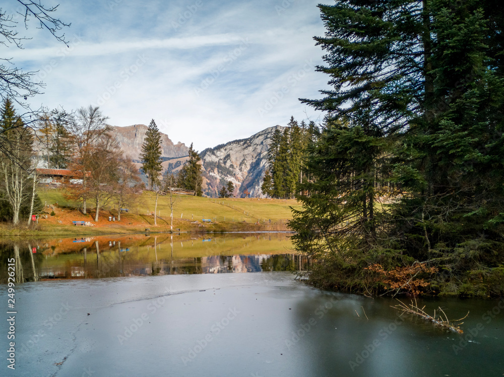 Chapfensee, Spiegelnder Stausee in der Schweiz, bei schönem Wetter mit Tannen und Bergen im Hintergrund