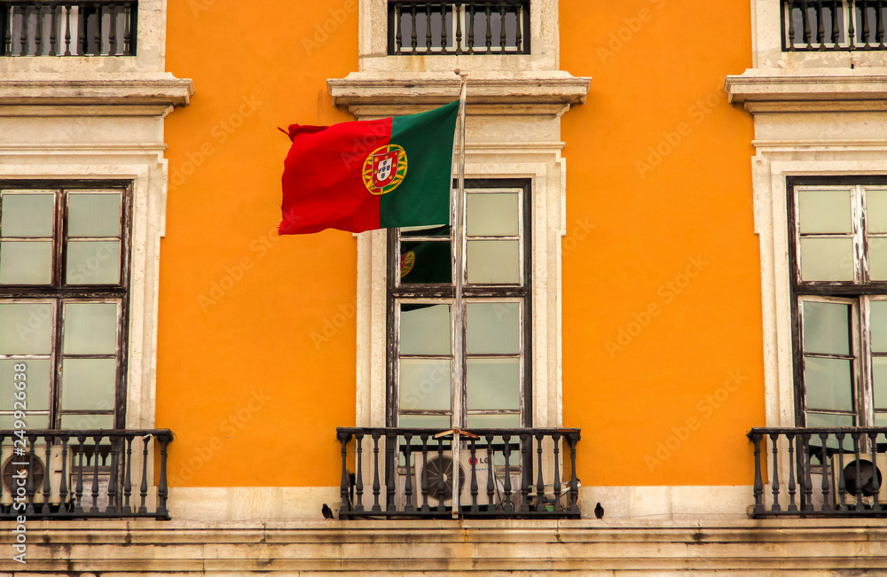 Flagge von Portugal vor einer traditionellen, gelben Hauswand