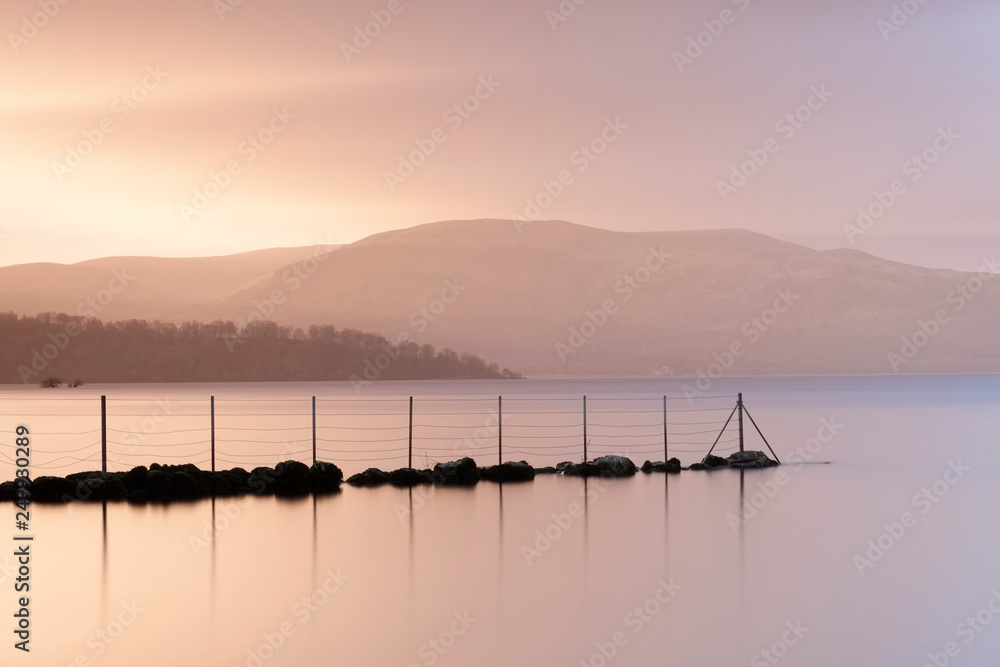 Sunset at Loch Lomond beautiful calm peaceful landscape scenic view reflection of jetty in water