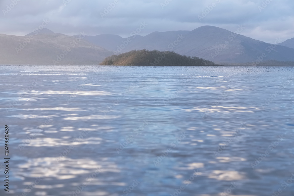 Calm peaceful atmospheric view of lake at Loch Lomond during change of weather from rain to sunshine