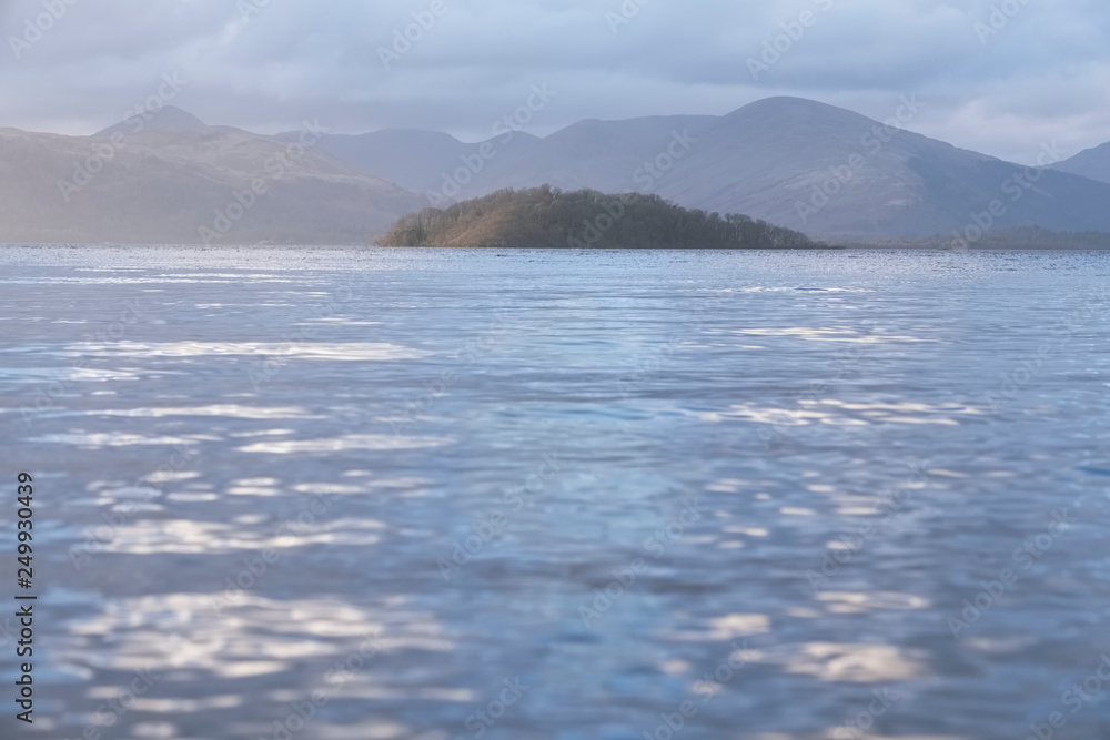 Calm peaceful atmospheric view of lake at Loch Lomond during change of weather from rain to sunshine Calm peaceful atmospheric view of lake at Loch Lomond during change of weather from rain to sunshine