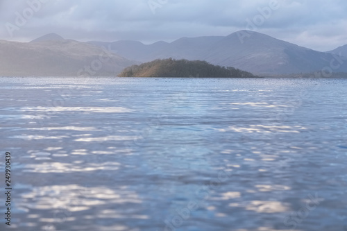 Calm peaceful atmospheric view of lake at Loch Lomond during change of weather from rain to sunshine