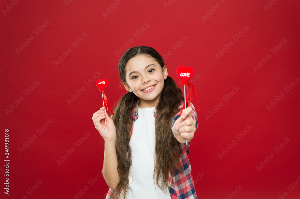 Giving love for you. Small girl holding hearts on sticks. Cute girl with small red hearts. Small child with heart shaped decorations. Happy valentines day. The holiday of love and romance Giving love for you. Small girl holding hearts on sticks. Cute girl with small red hearts. Small child with heart shaped decorations. Happy valentines day. The holiday of love and romance