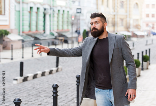 A hitchhiker. Professional businessman leading busy lifestyle. Bearded man going to work. Hipster in business style on street. Business man in modern city. The beginning of working day