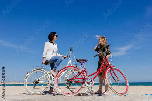Two friends on the beach with bicycles