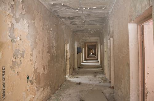 The interior of an abandoned old building. A long corridor with entrances to rooms without doors. © bisonov